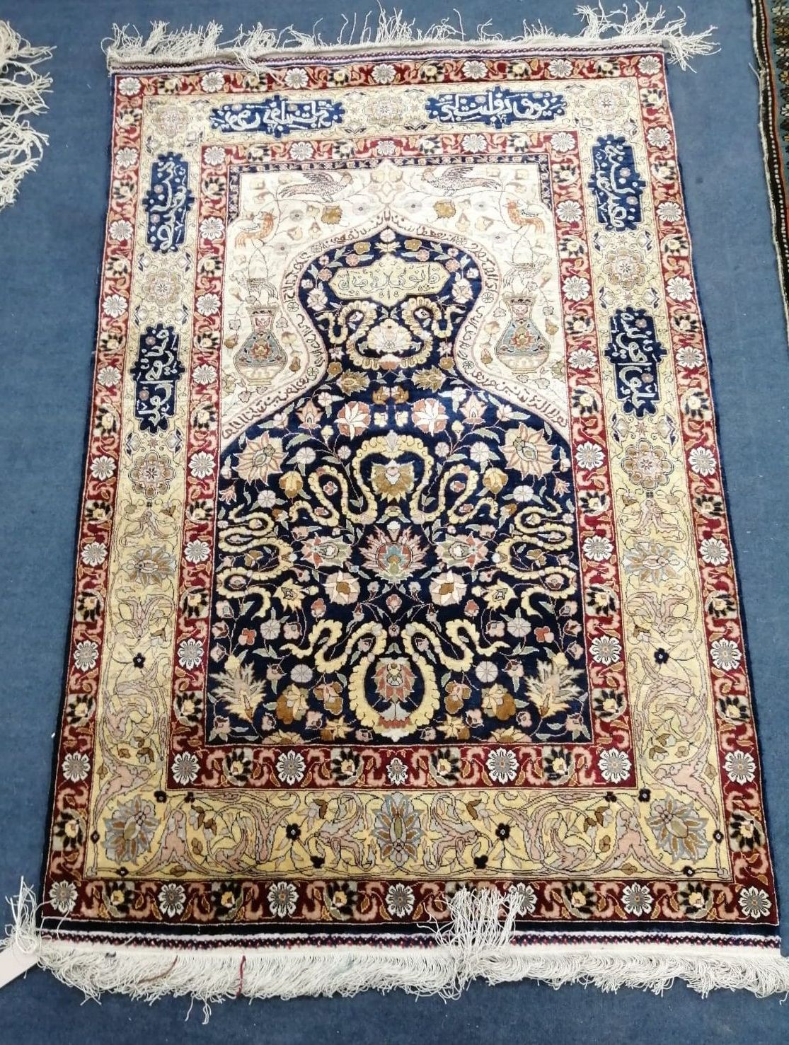 A small Persian silk rug centred with a calligraphic medallion, 42 x 90cm